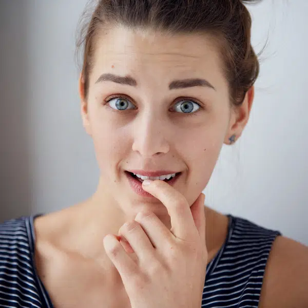 Primo piano di donna imbarazzata che morde un dito a causa di cattivo odore intimo vaginale