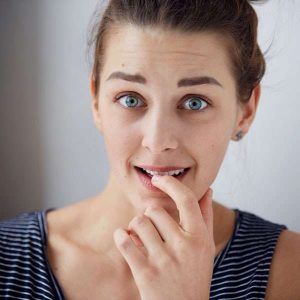 Primo piano di donna imbarazzata che morde un dito a causa di cattivo odore intimo vaginale